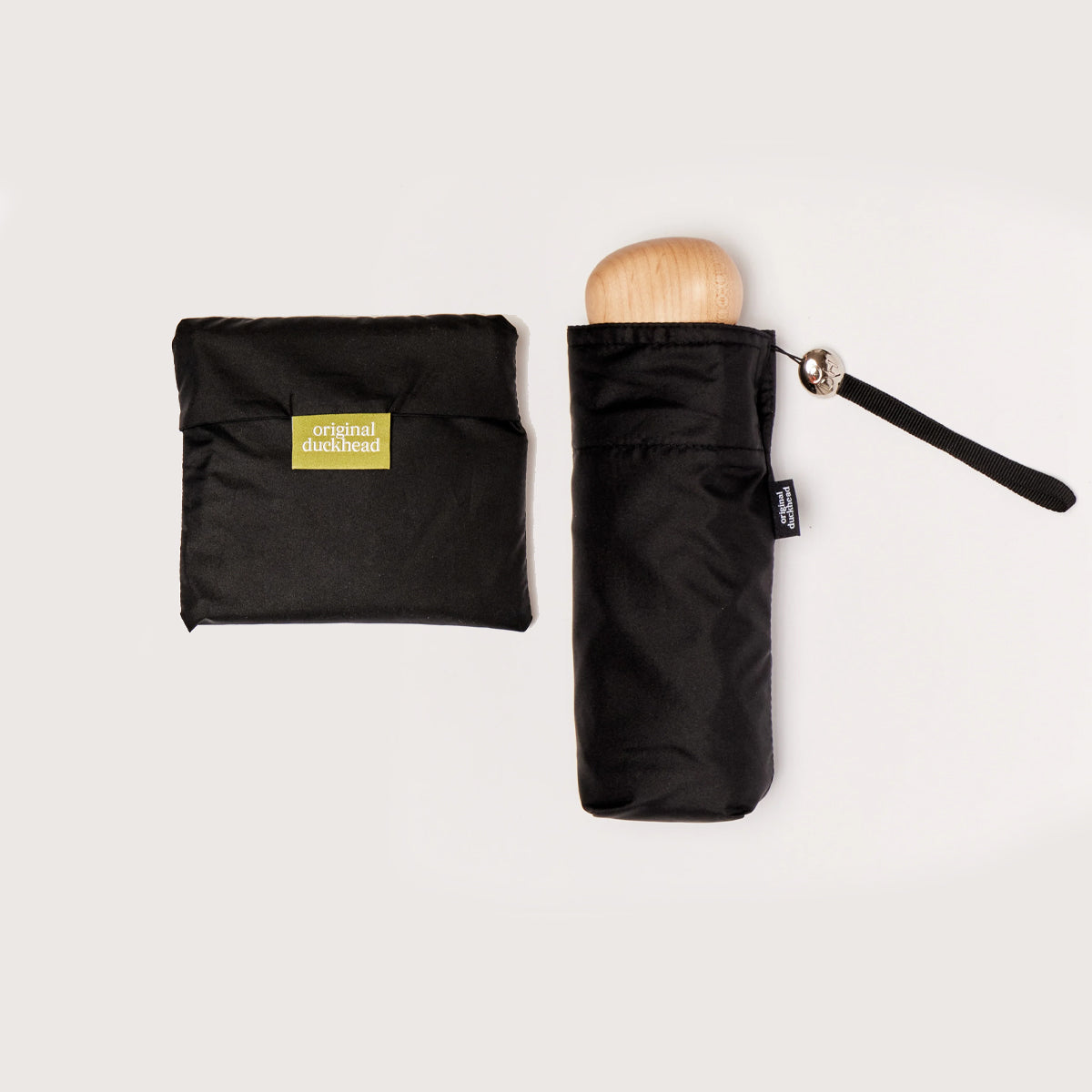 Black folded umbrella with wooden handle and matching pouch on a light background