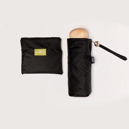 Black folded umbrella with wooden handle and matching pouch on a light background