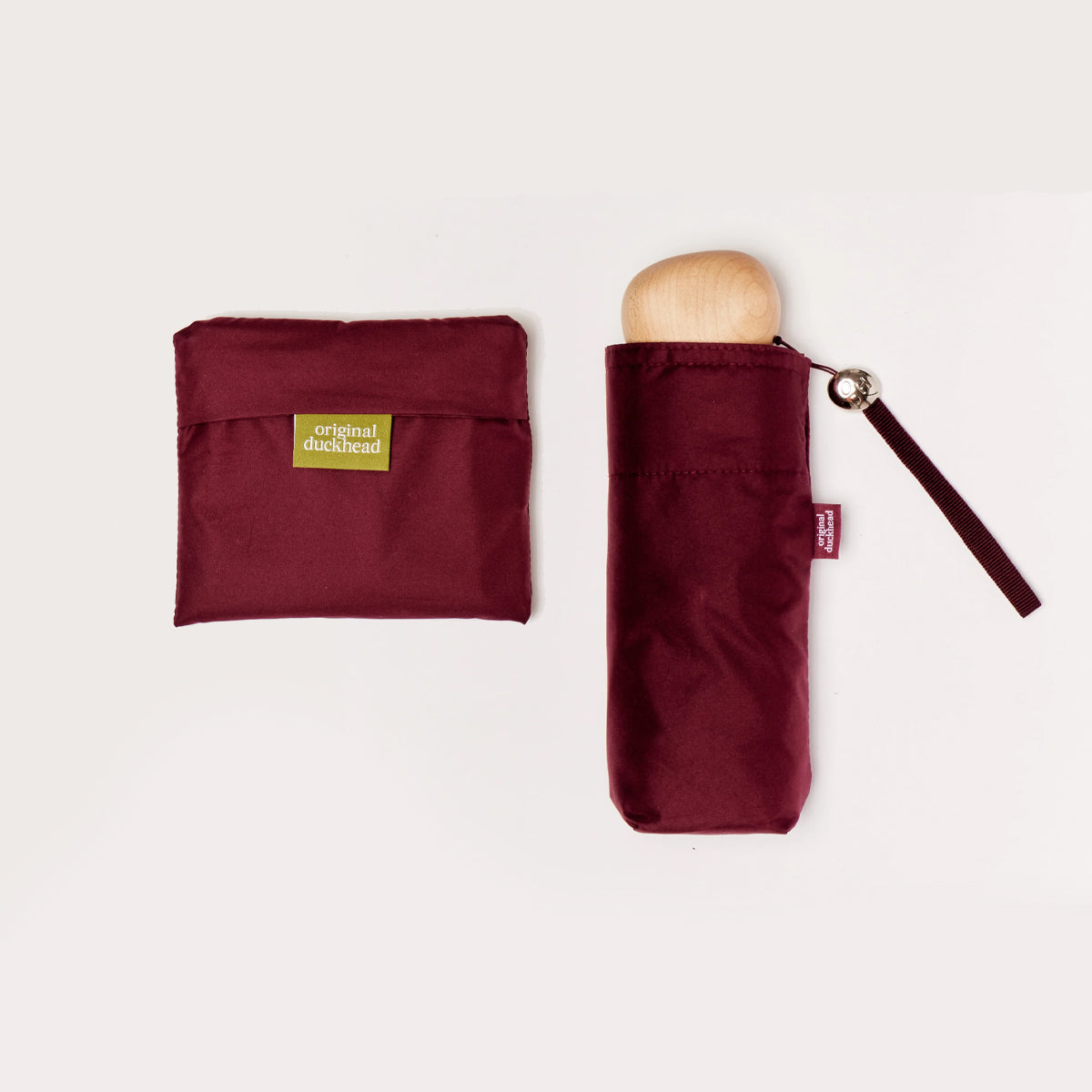 Cherry red umbrella with wooden handle and matching pouch on a plain background