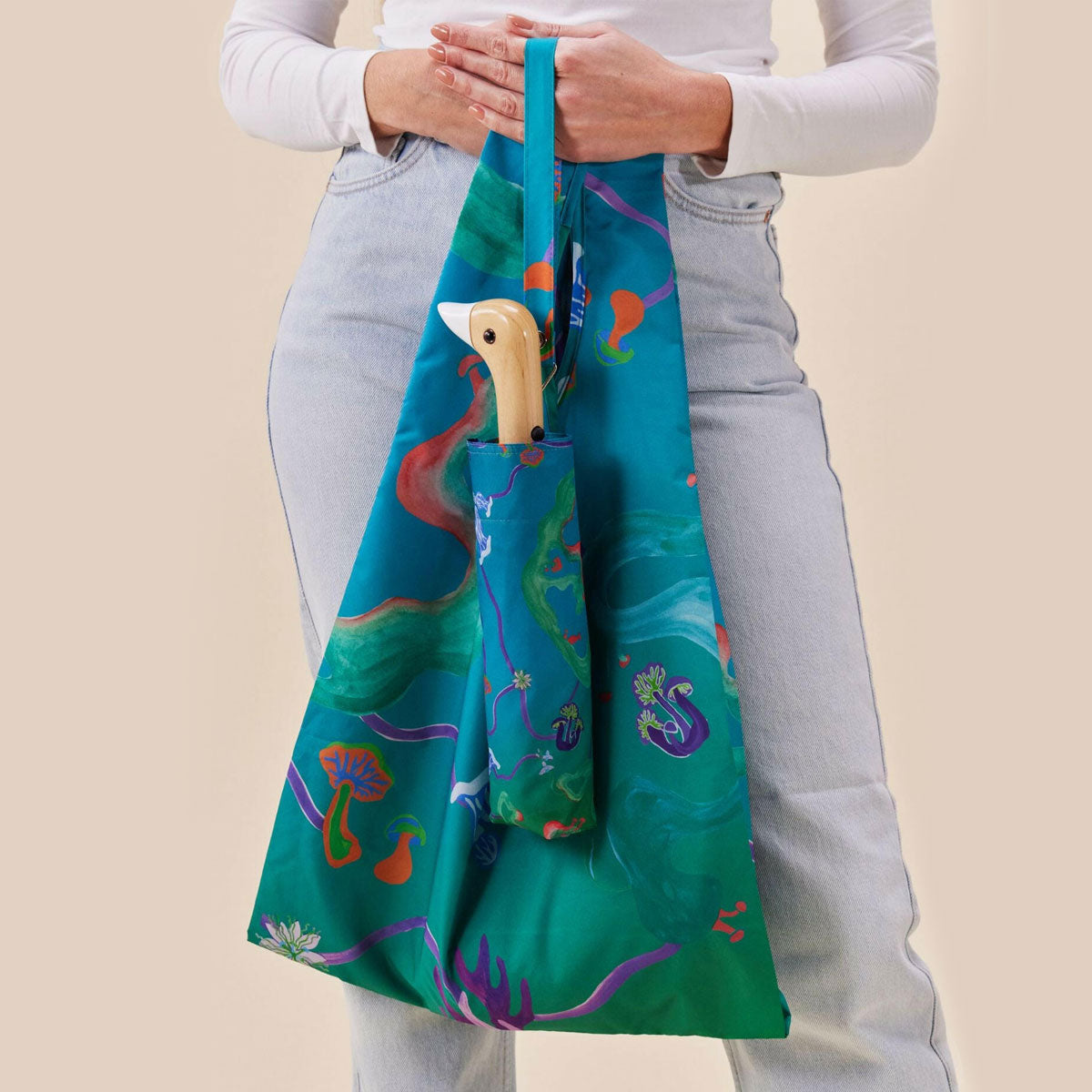 Person holding a colorful bag and matching umbrella with duckhead wooden handle