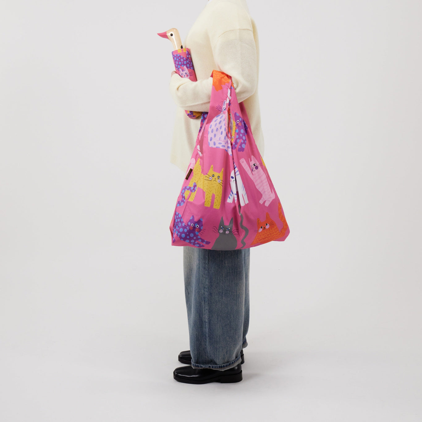 Person holding a colorful bag with cat designs on a plain background