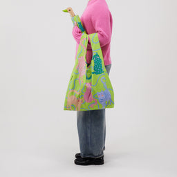 Person holding a colourful umbrella with duckhead handle and a matching tote bag with cat designs on a white background