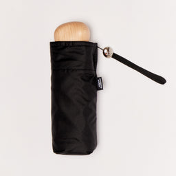 Black mini umbrella with wooden handle on a light background
