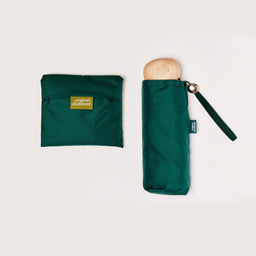 Green umbrella folded and folded tote bag in pouch on a light gray background