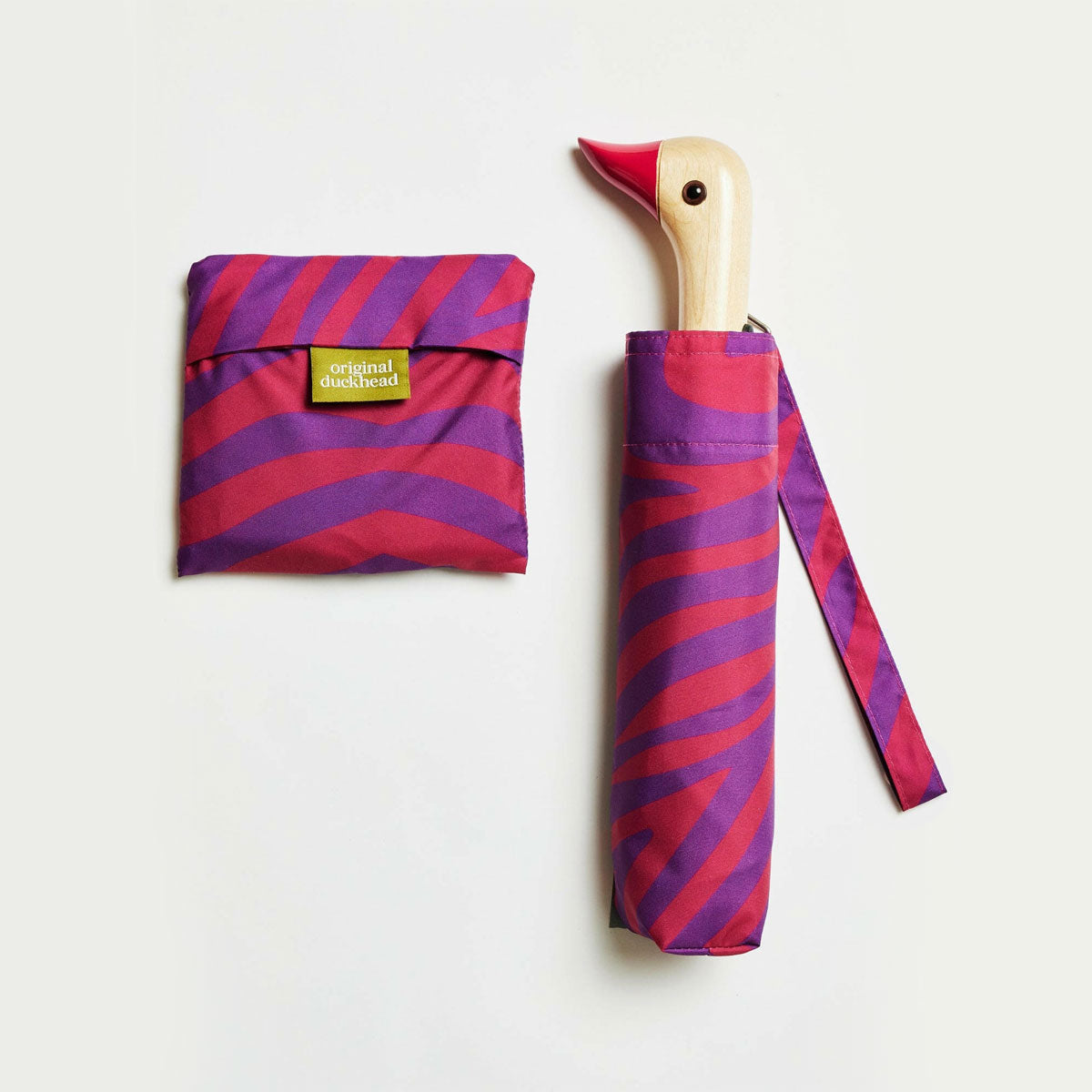 Purple and pink striped umbrella with duckhead wooden handle on a white background