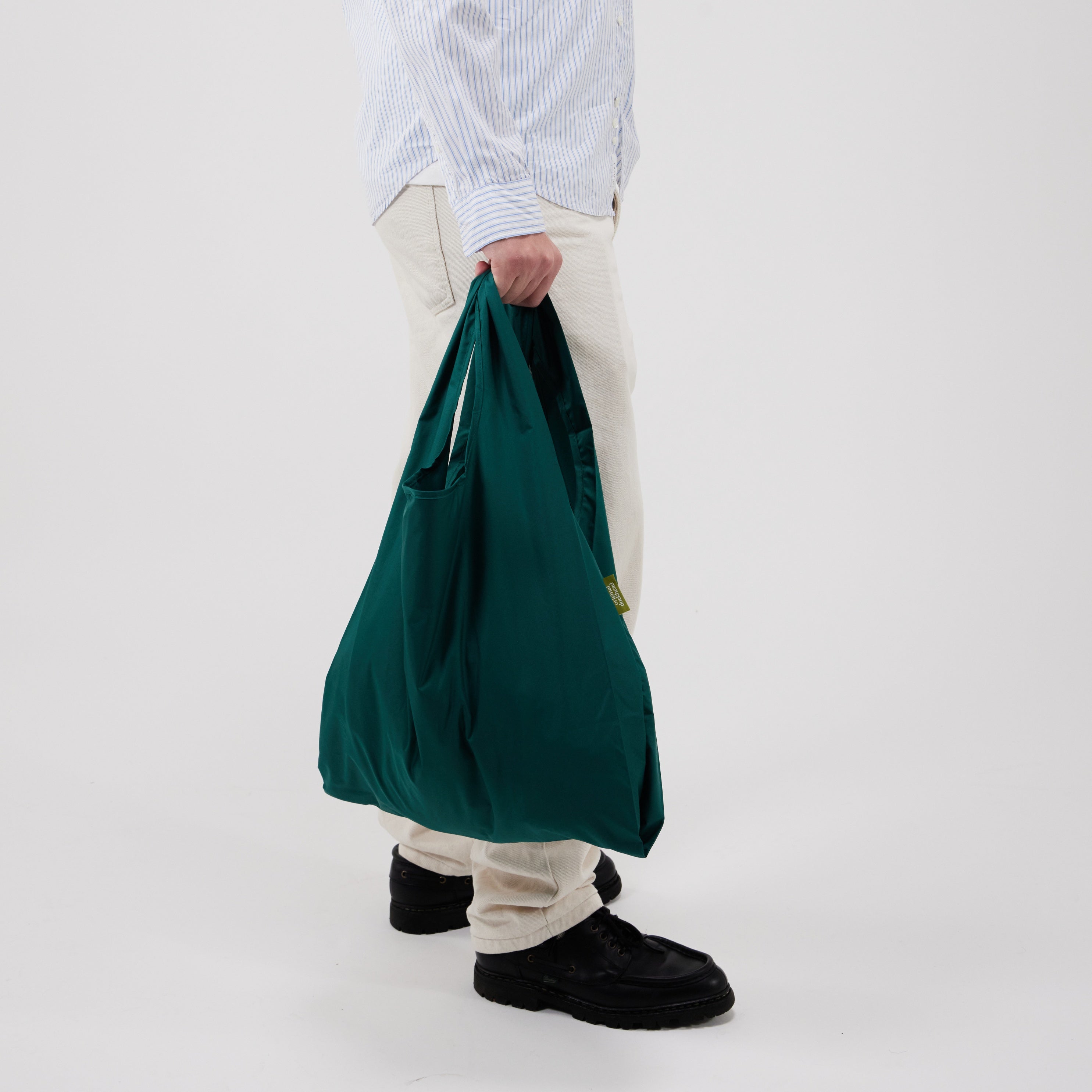 Person holding a green bag against a white background